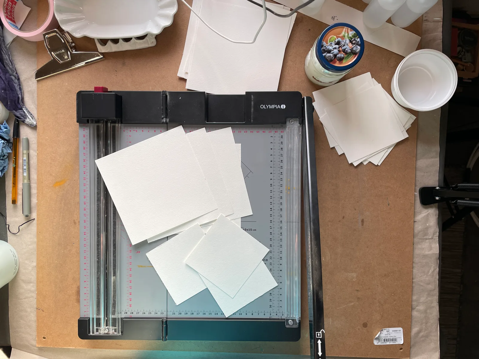 Hebelschneider mit frisch zugeschnittenem Aquarellpapier auf Künstlertisch mit Materialien