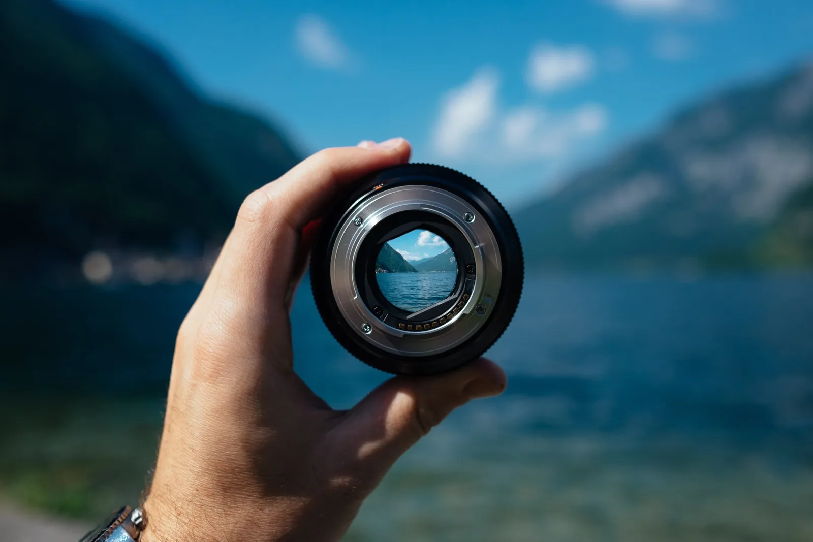 Kameralinse in Hand mit Bergseepanorama Fokus-Symbol für Leadmagnet-Erstellung