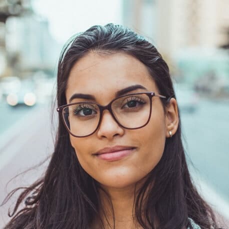 Porträt einer Frau mit Brille, dunklen Haaren und urbaner Hintergrund-Unschärfe, Kundenstimme