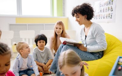 Lerncoach Ausbildung – Zertifikatskurs für Lernbegleitung 5 Kindergärtnerin liest mit Kindern im Kreis an gelbem Sitzsack in heller Kita