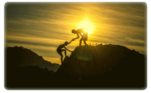 Silhouetten zweier Personen helfen sich gegenseitig auf Bergspitze bei Sonnenaufgang