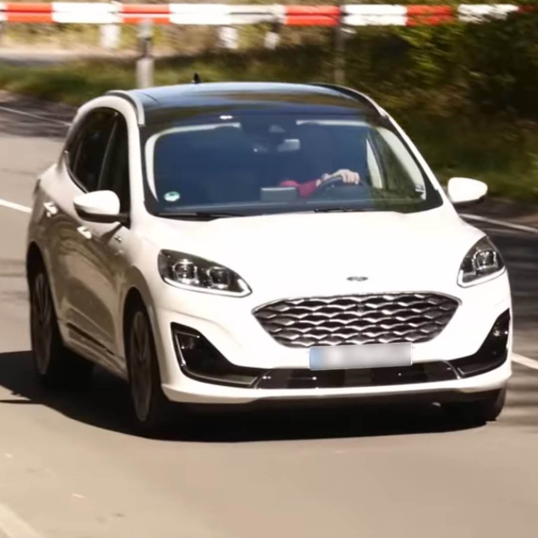 Weißer Ford Kuga II in Fahrt auf Landstraße mit Fahrer