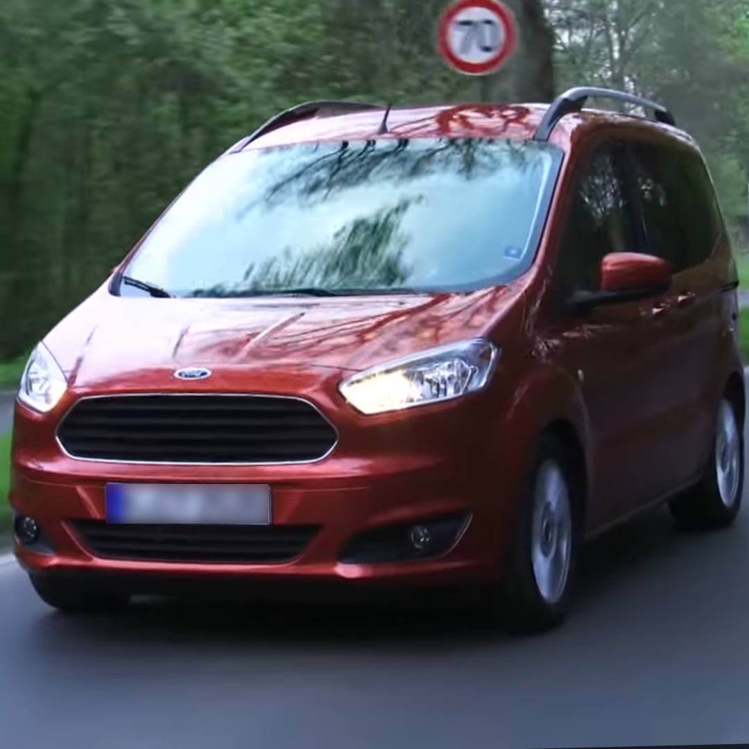 Roter Ford Tourneo Courier auf Waldstraße, Seitenansicht des kompakten Vans