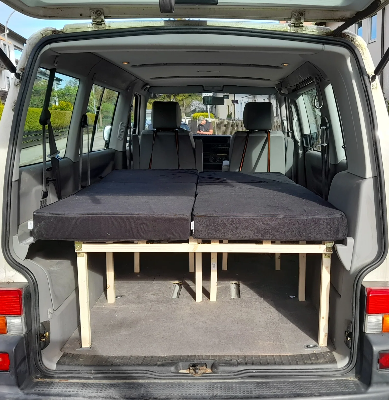 VW T5 Transporter mit ausgebautem Doppelbett aus Holz und dunkelgrauer Matratze