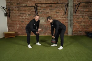 Zwei Männer in Sportkleidung mit Kettlebell beim funktionellen Training