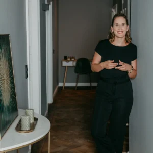 Kerstin Schimkus in schwarzem Shirt gestikulierend in modernem Raum mit Dekorelementen