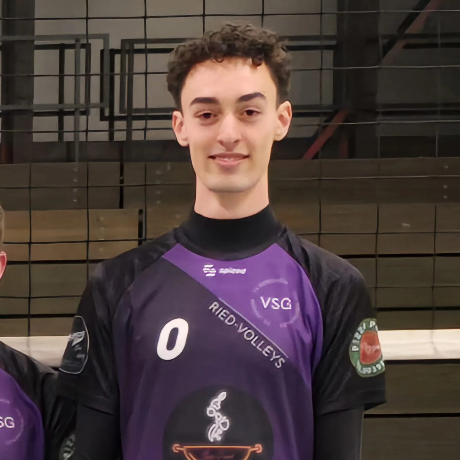 Volleyballspieler Amir Heisig in violettem VSG Riedvolleys Trikot vor Netz