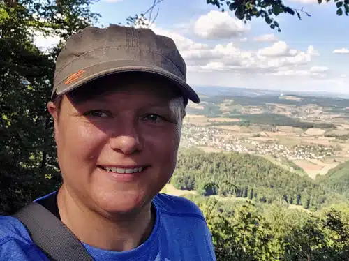 Karin Zeilinger Selfie mit Cap vor Aargau-Landschaft, Wald und Hügellandschaft