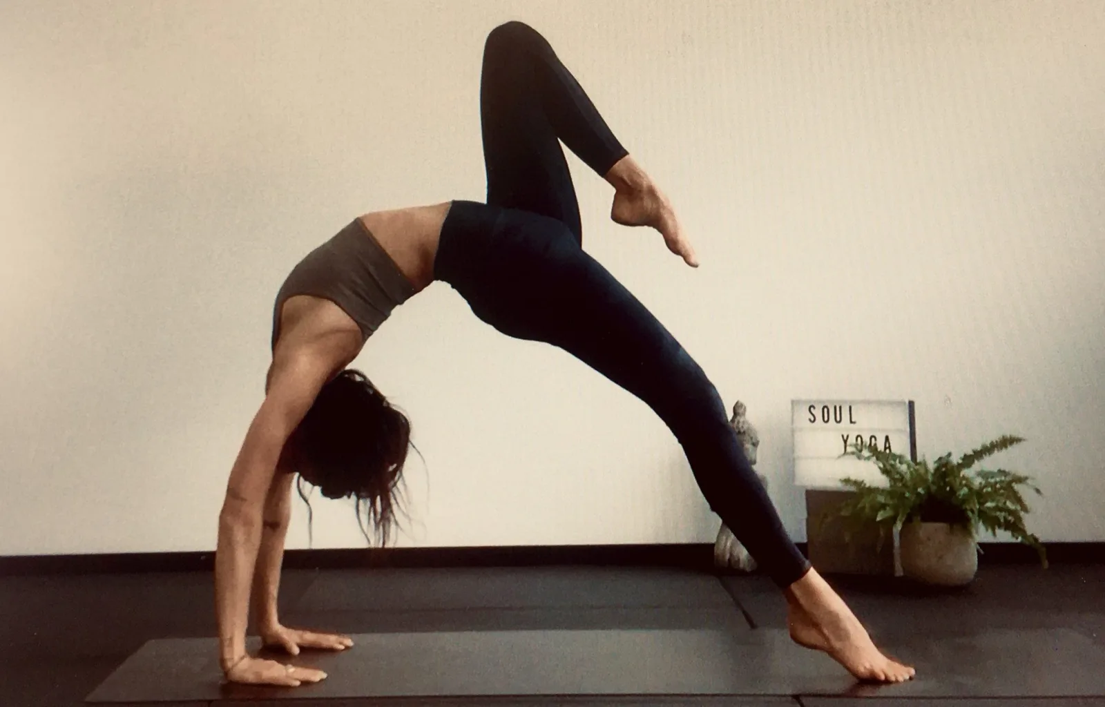 Frau in Yoga-Pose am Boden neben Pflanze und Soul Yoga Schild