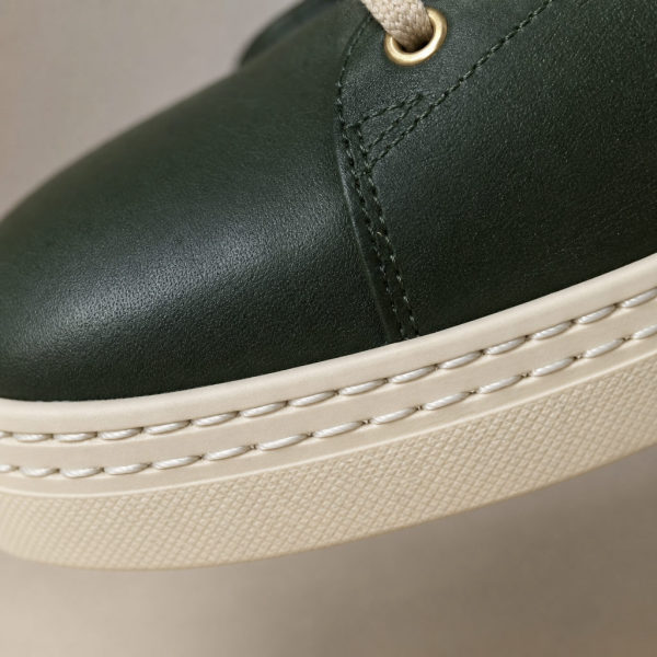 Detailaufnahme grünes Leder mit Nahtwerk und cremefarbene Sohle