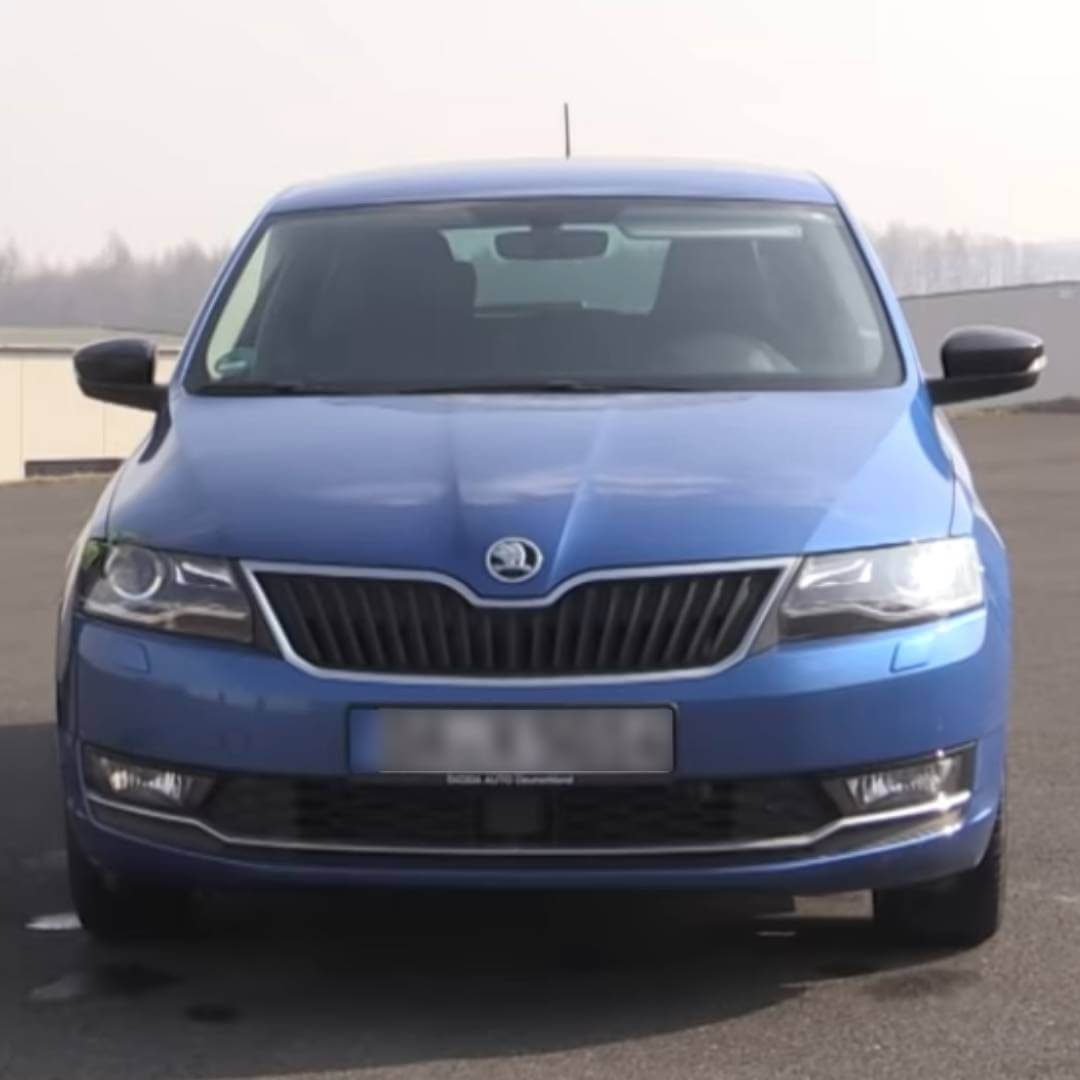 Lit double Skoda Rapid – E-Book-Bauanleitung Auto-Bett 3 Skoda Rapid Frontansicht auf Parkplatz, blaue Limousine mit Skoda-Logo