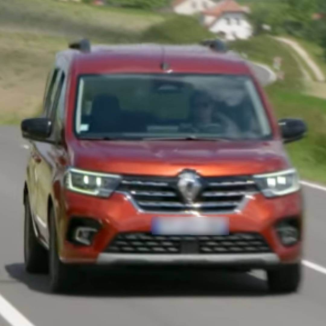 Renault Kangoo W rot, Frontansicht auf Straße mit grünem Hintergrund