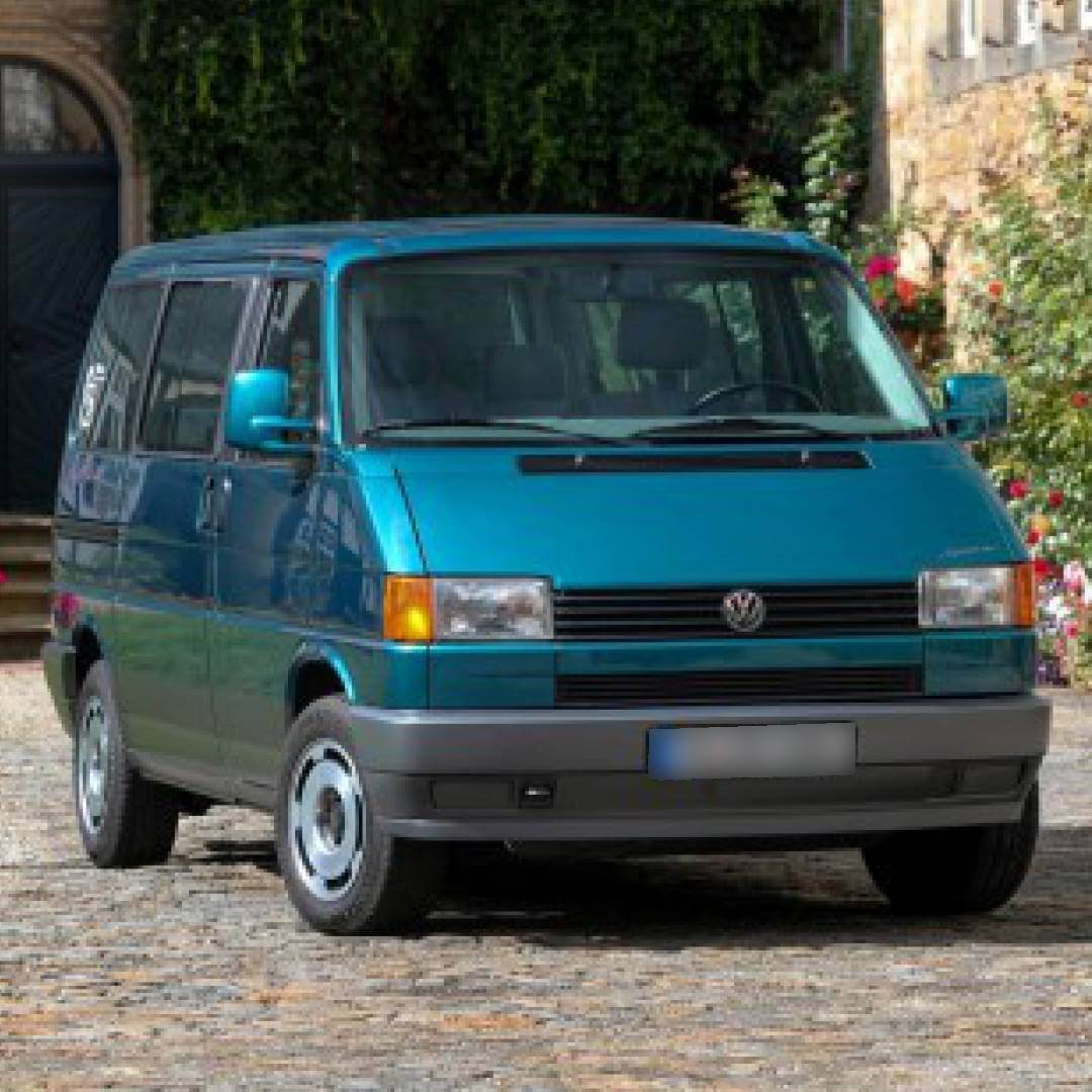Türkisfarbener VW T4 Transporter, Frontansicht, Außenaufnahme vor Heckenlandschaft