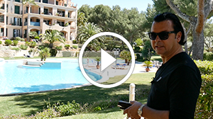 Videostandbild: Mann vor Luxus-Villa mit Pool und Play-Symbol
