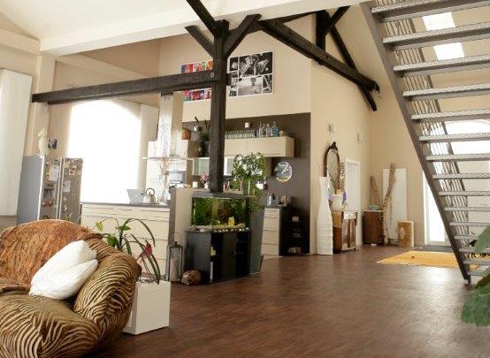 Modernes Loft-Interieur mit hohen Decken, dunklen Balken, Treppe und großen Fenstern