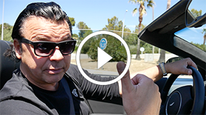 Videostandbild: Mann in Cabrio vor Immobilien-Projekt mit Play-Symbol