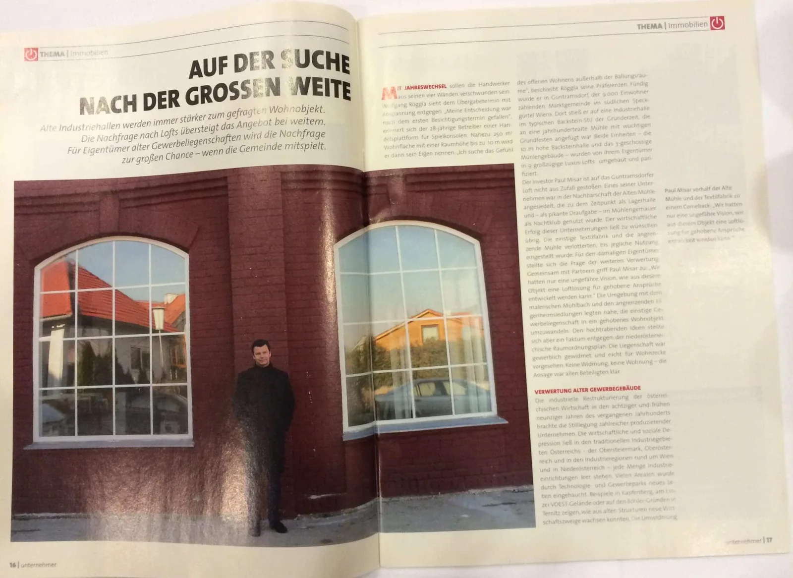 Magazin-Doppelseite mit Artikel über Loft-Umnutzung, Überschrift und Mann vor großen Fenstern