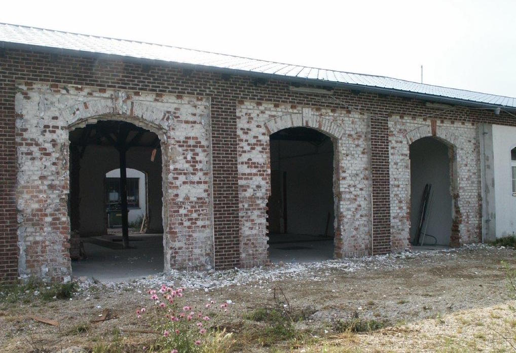 Verfallene Industriegebäude mit Backsteinbogen und Blütenbusch