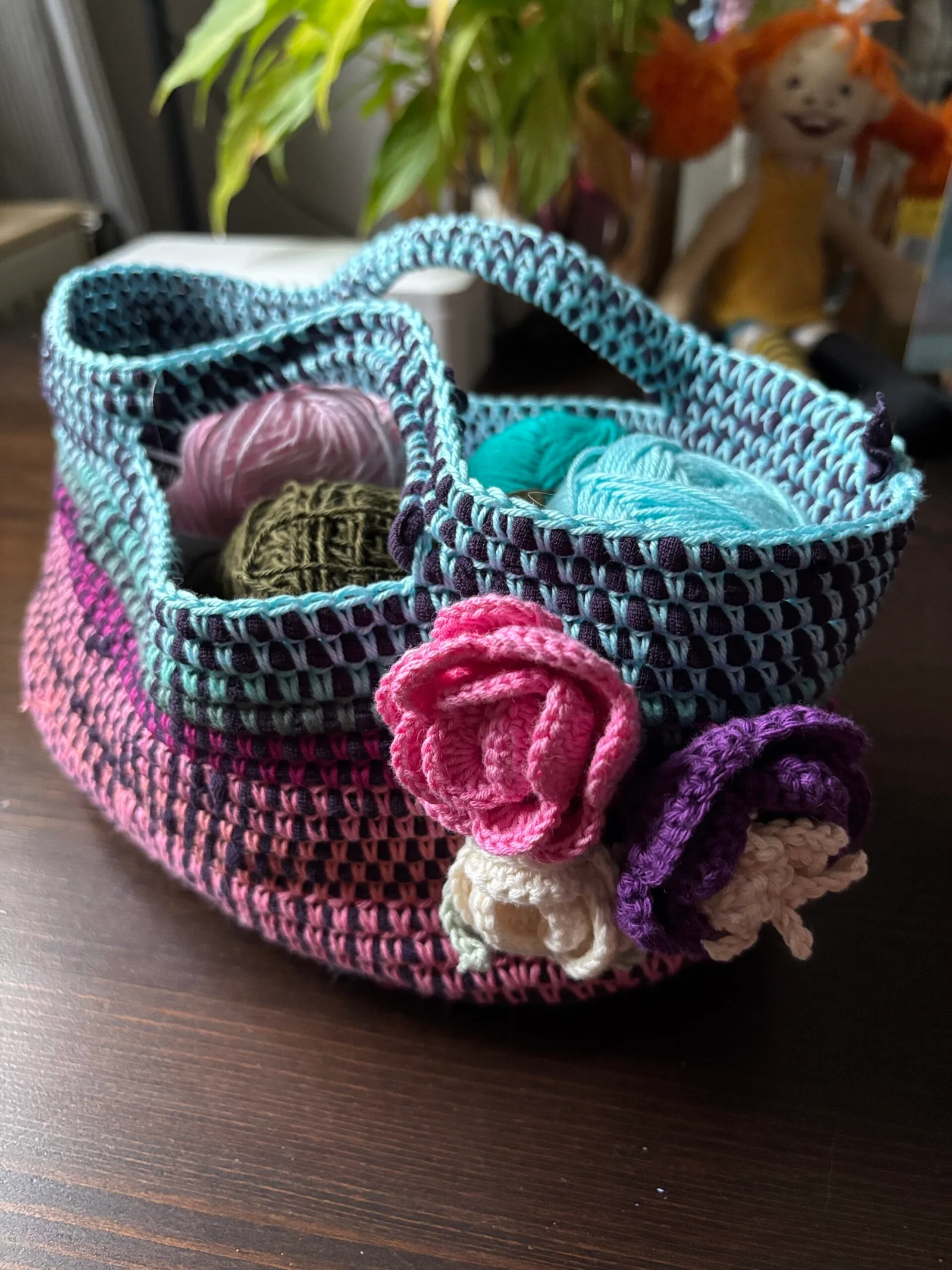 Farbenfroher gehäkelter Körbchen aus Utensilos in Türkis, Pink und Violett mit bunten Wollknäueln