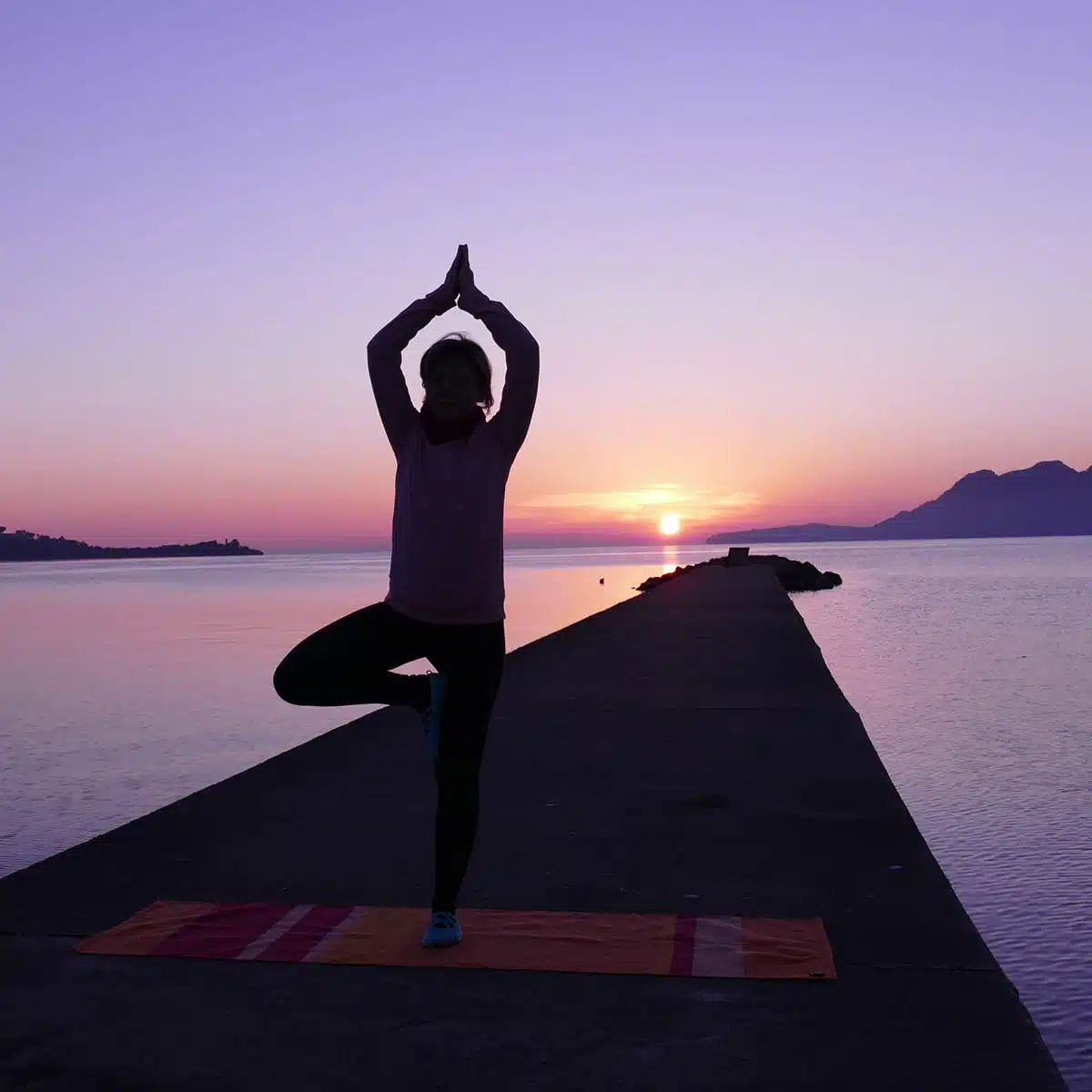 Magische Rauhnächte – Yoga- und Meditationskurs von Yoga mit Martina 6 Frau in Yoga-Baum-Position bei Sonnenaufgang am Meer, Yoga-Praxis während Rauhnächte