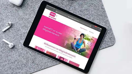 iPad zeigt mamaFIT on screen Website mit pinkem Logo und Trainerin im Video