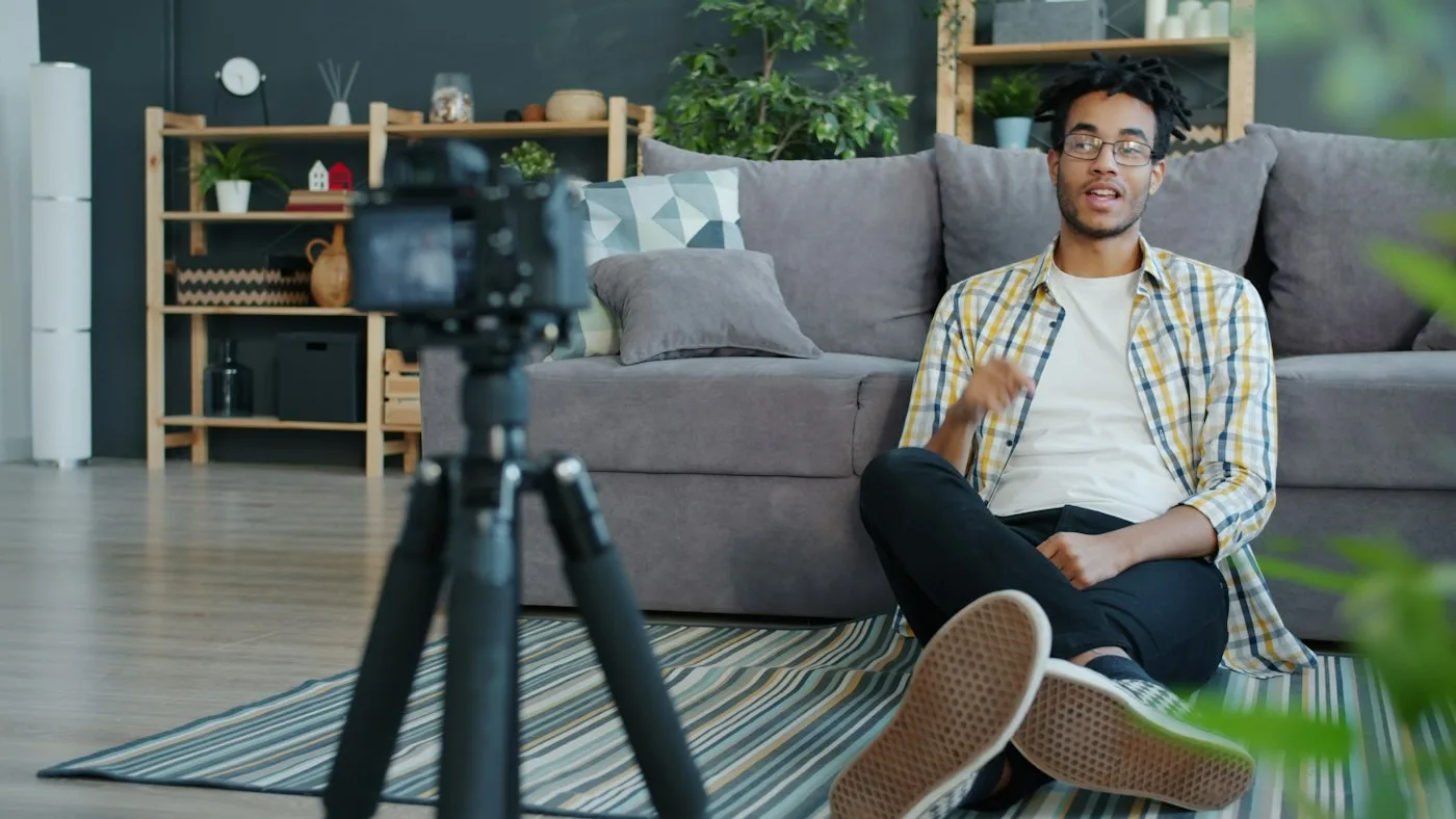 Mann sitzt auf Sofa und spricht vor Kamera für Videokurs im Home Studio