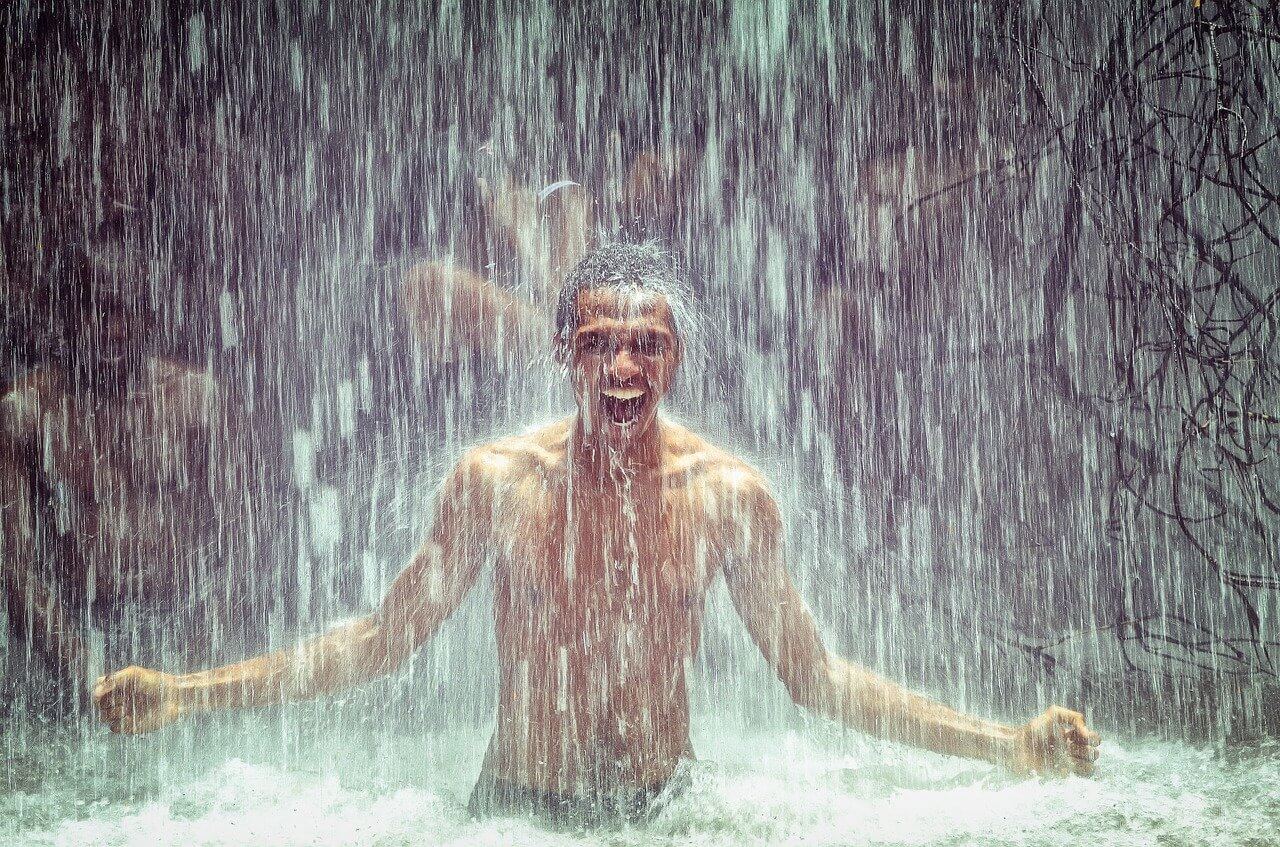 Person hebt Arme im Regen, symbolisiert innere Stärke und Entschlossenheit