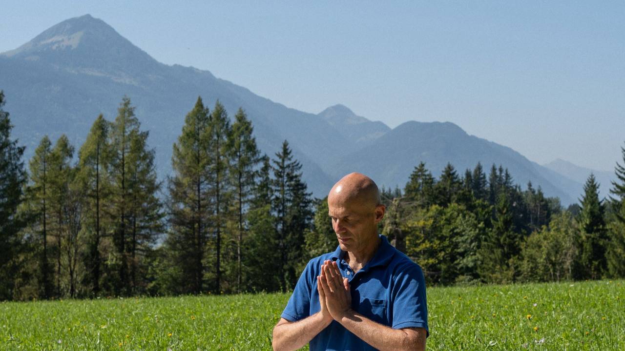 Christian Opitz meditiert in Berglandschaft mit Händen vor Brust