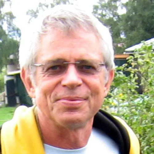 Älterer Mann mit grauem Haar und Brille in Freizeitkleidung vor grünem Garten-Hintergrund