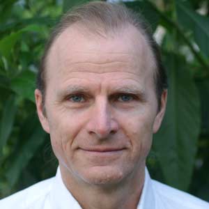 Portrait Dieter Berweiler mittlerer Altersmann mit Brille vor grünem Blätter-Hintergrund