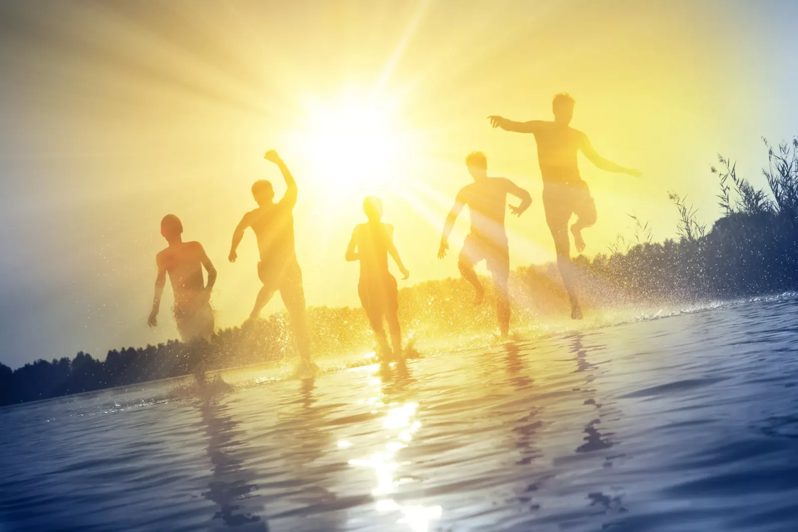 Mehr Glück, mehr Lebensfreude – 99 kraftvolle Zitate von Dejan Sekulic 2 Gruppe von Kindern und Erwachsenen läuft fröhlich ins Meer bei Sonnenuntergang