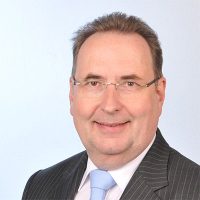 Jörg Uhlenbruck, Mann mit Brille und grauem Anzug, Porträt