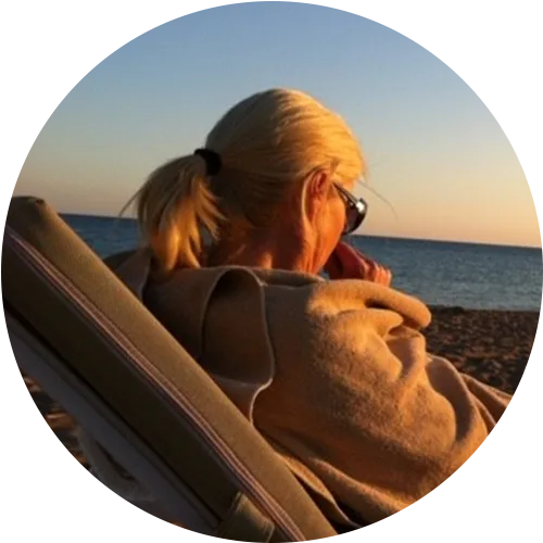 Frau mit Sonnenbrille entspannt am Strand in der Abendsonne