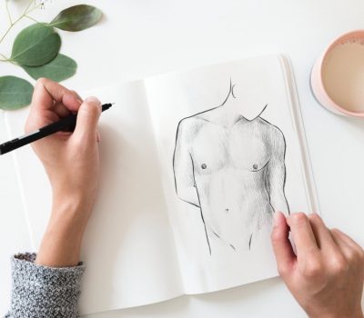 Hände skizzieren männliche Torso-Anatomie mit Bleistift auf Papier