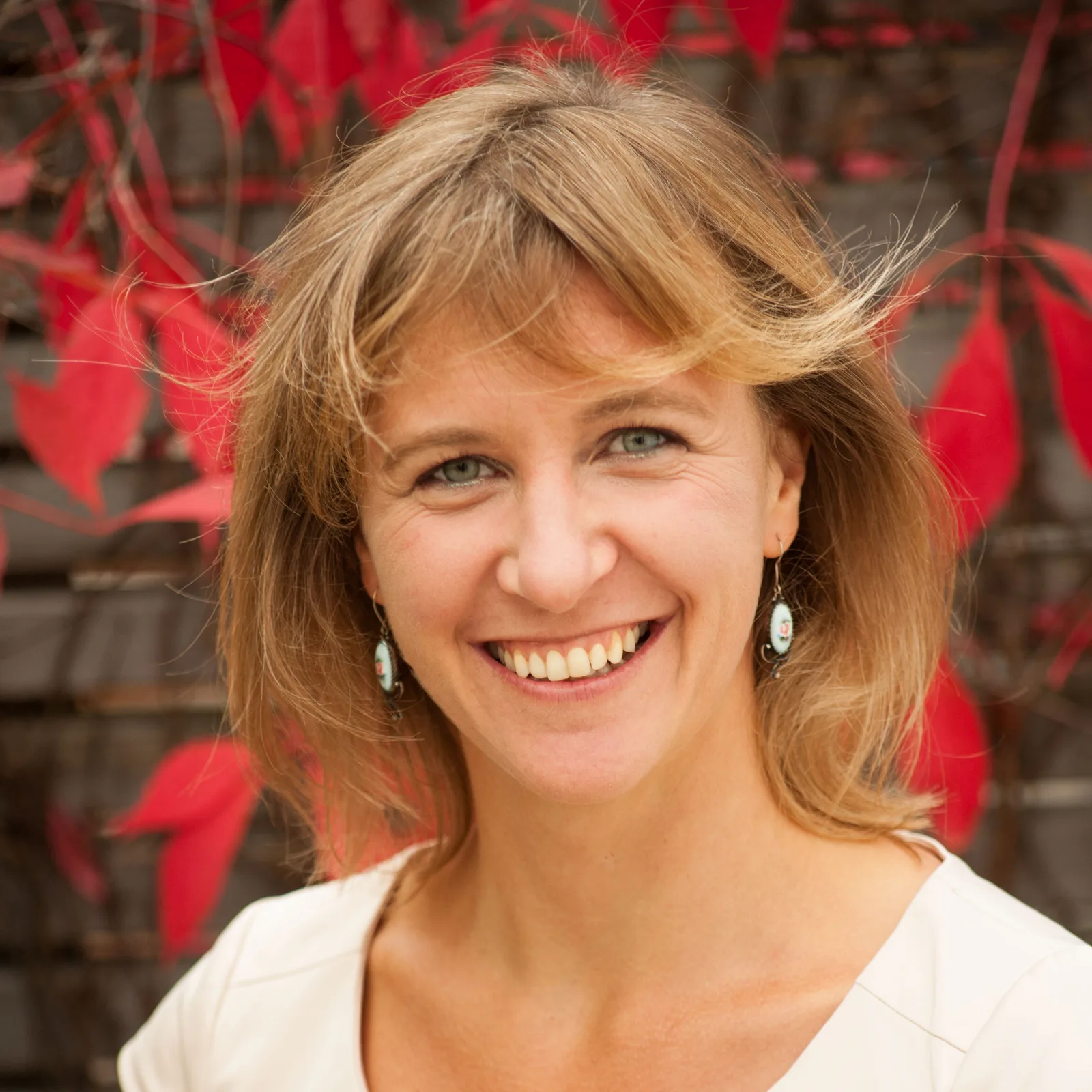 Elke Wünnenberg, Frau mit braunen Haaren und rotem Hintergrund, Profilbild