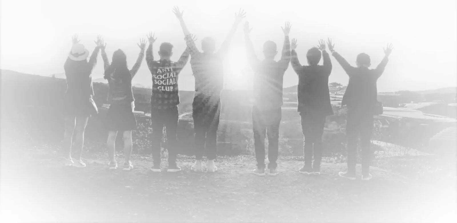 Gruppe von Menschen mit erhobenen Händen in Silhouette, Outdoor-Setting mit überbelichteten Effekt