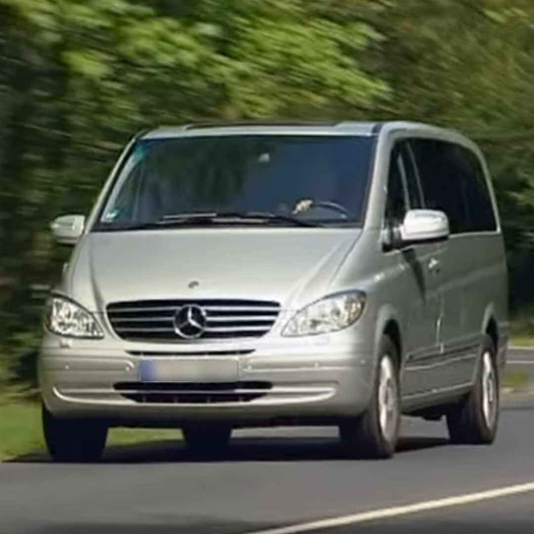 Silberner Mercedes Viano in Bewegung auf einer Straße mit grünem Hintergrund