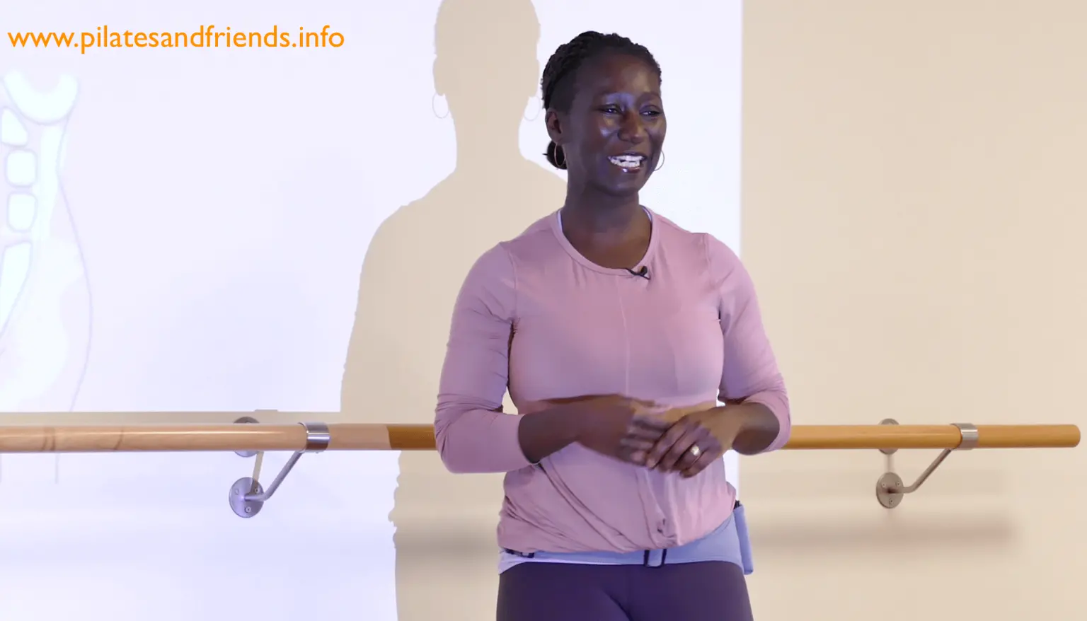 Frau in lila Shirt vor Spiegel, Website-URL www.pilatesandfriends.info oben links