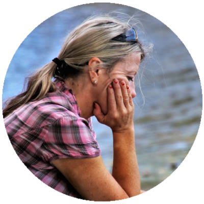 Frau am Meer sitzt nachdenklich, Hand im Gesicht, emotionales Portrait