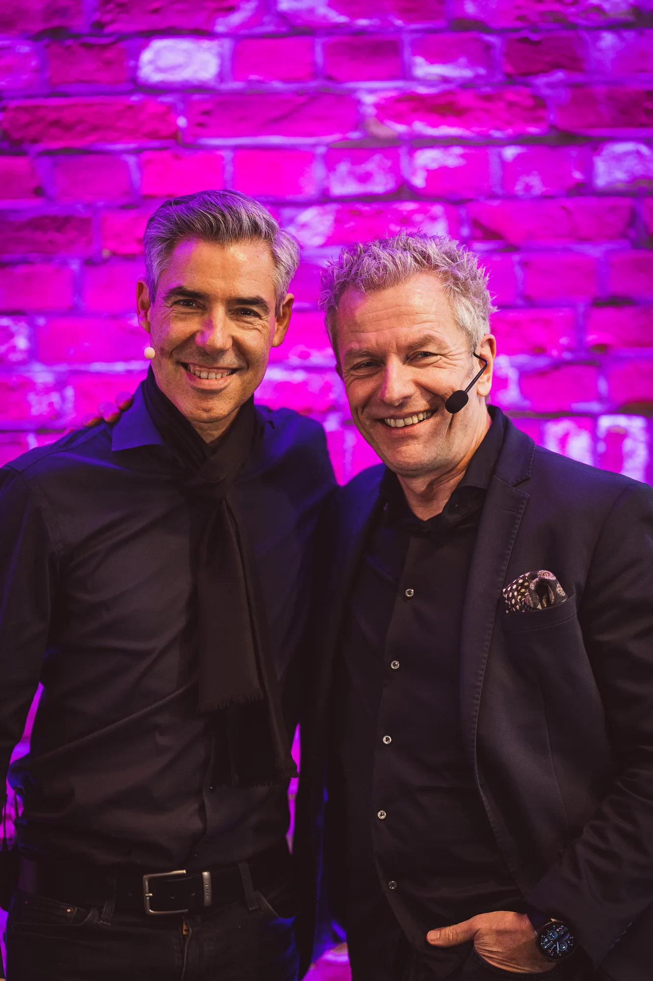 Frank Asmus und Andreas Enrico Brell vor pinker Backsteinwand mit pinker Beleuchtung
