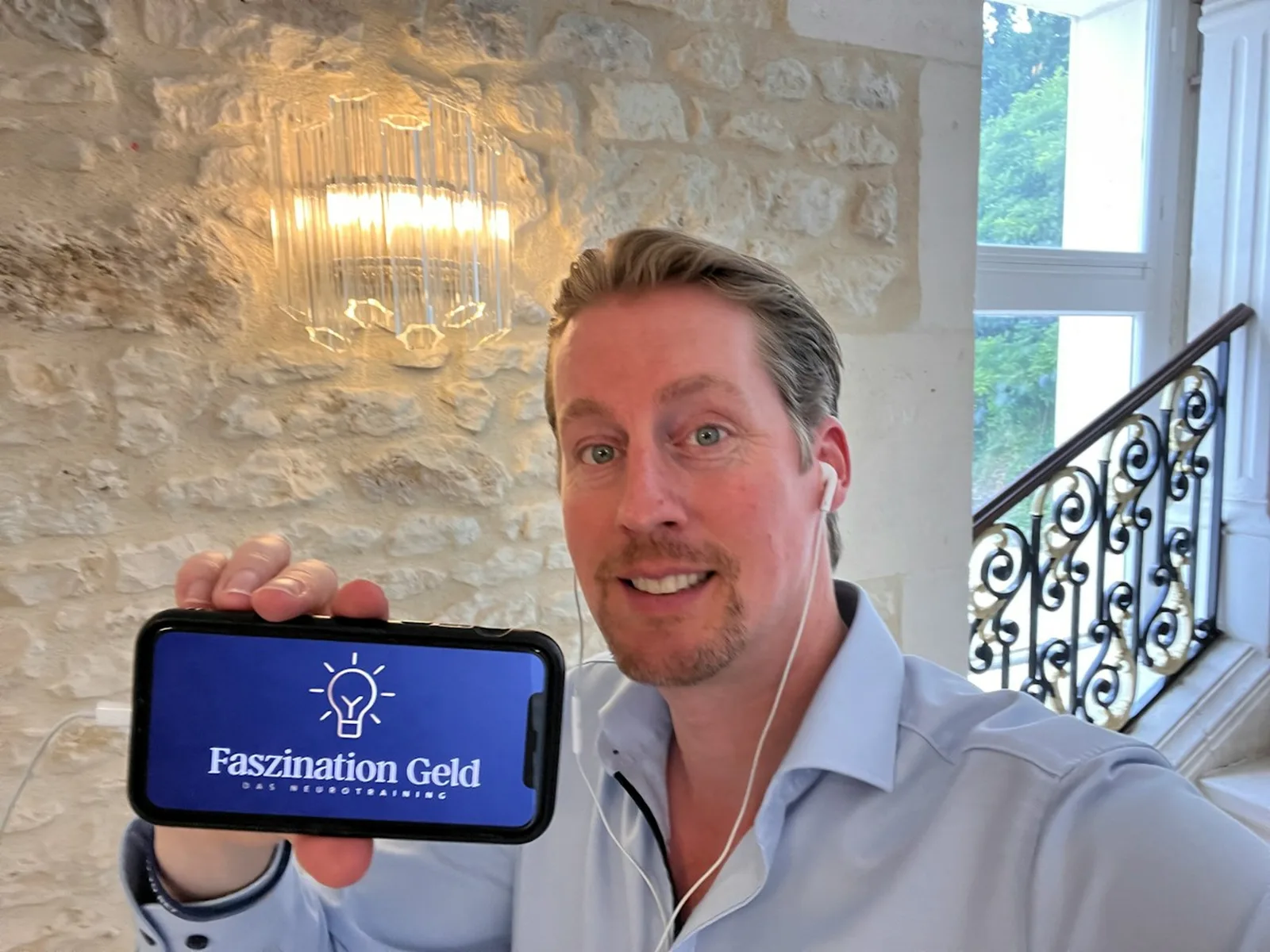 Daniel Weinstock präsentiert Faszination Geld Logo auf Smartphone