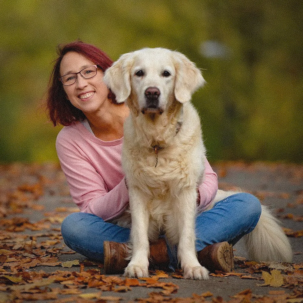 Money Mindset Shifted – Videokurs zu Geldglaubenssätzen 3 Frau mit dunkelroten Haaren, Brille und rosa Shirt mit gelbem Labrador-Retriever, Herbstlaub