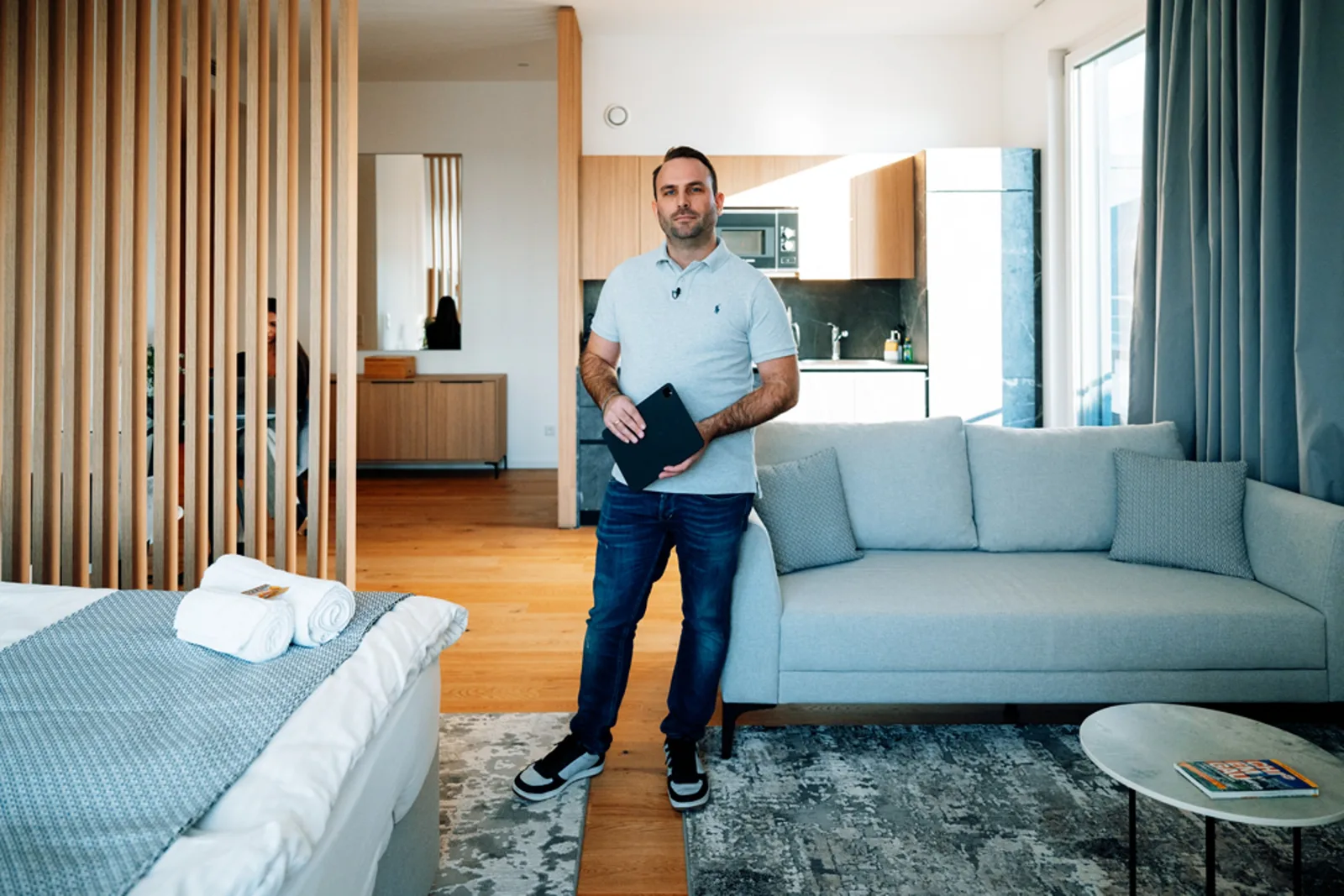 Mann in hellblauem Poloshirt präsentiert Tablet in modernem Apartment