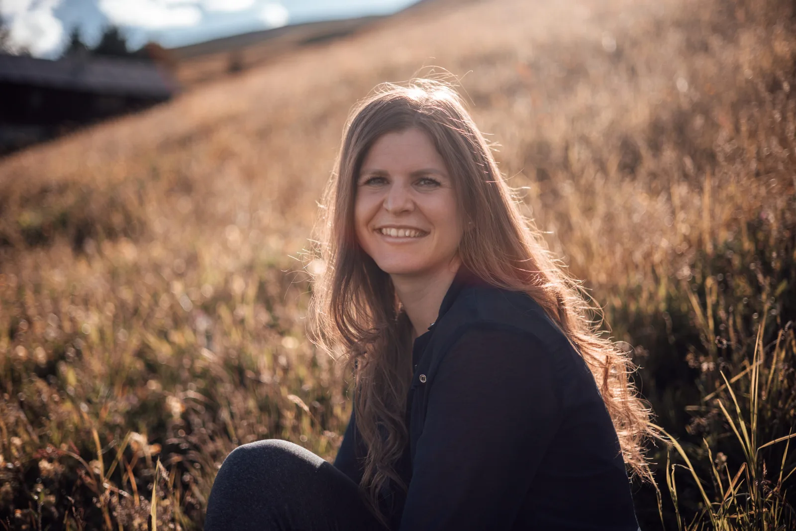 Jana Berger, Autorin des Morgenroutine Online-Kurses, lächelnd in einem Feld bei Sonnenaufgang