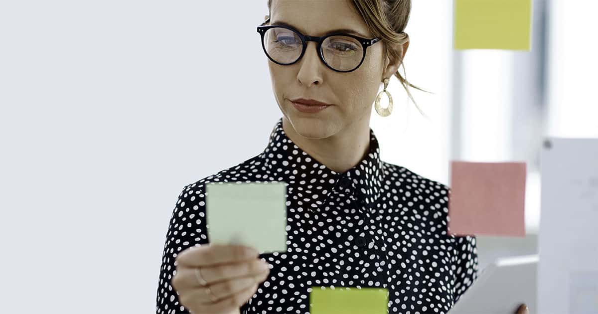 Frau mit Brille und Polka-Dot-Bluse hält grüne Notiz, Hero-Banner MotiLern TrainerGeheimnisse