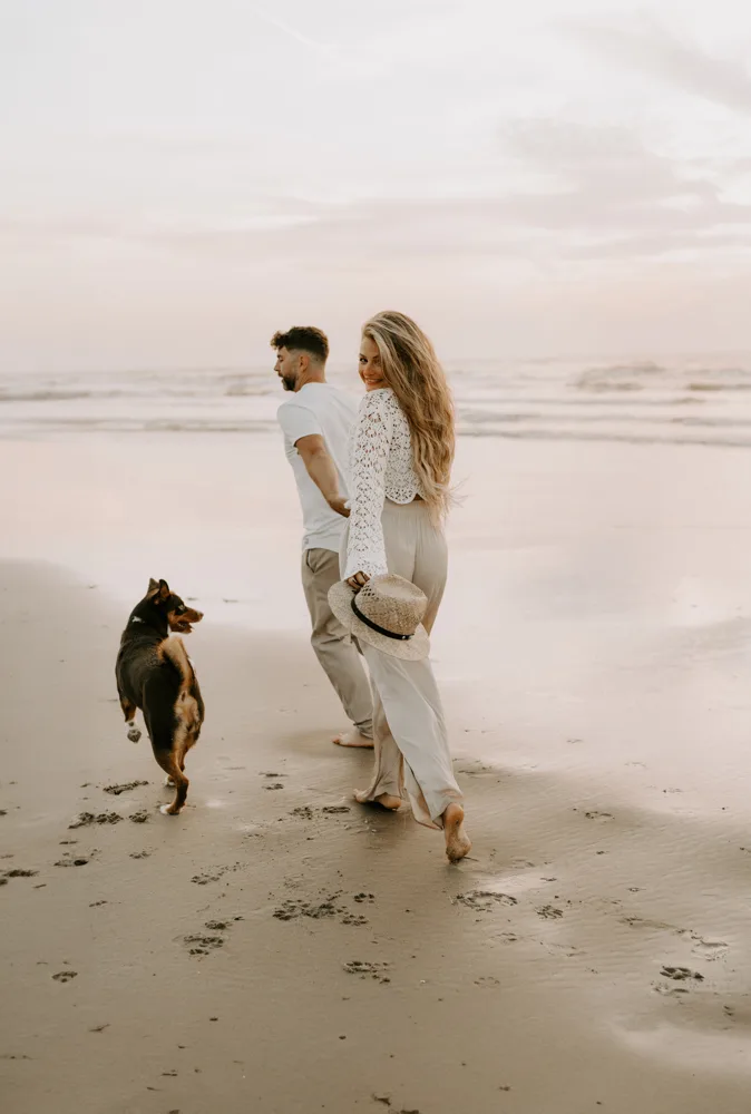 Paar mit schwarzbraunem Hund am Strand Zandvoort, entspannt