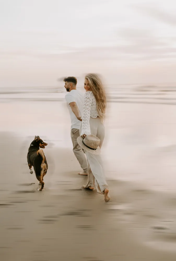 Paar mit schwarzbraunem Hund am Strand mit Motion Blur Effekt