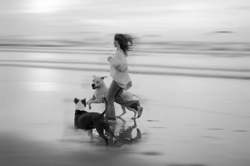 Frau mit drei Hunden am Strand, Motion Blur Effekt auf gesamtem Bild
