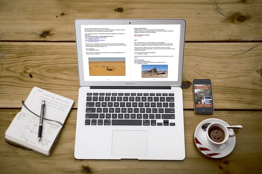 Laptop und Smartphone zeigen eBook-Inhalte mit Wüstenszene auf Holztisch