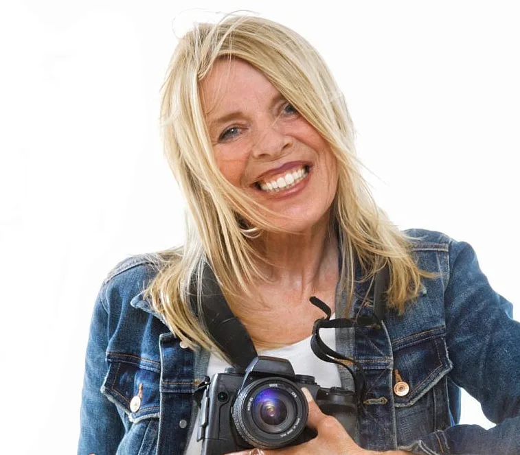 Natürlich fotogen! – Videokurs für Posing vor der Kamera 10 Porträt einer blonden Frau mit Kamera, Denim-Jacke, lächelnd gegen weißen Hintergrund